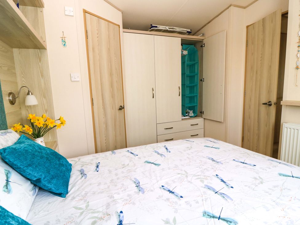 A bedroom with a bed and wardrobe at Beachcombers in Wareham