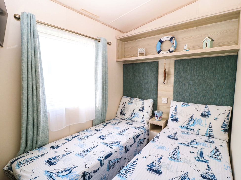 A bedroom with two beds and decorative items at Beachcombers in Wareham