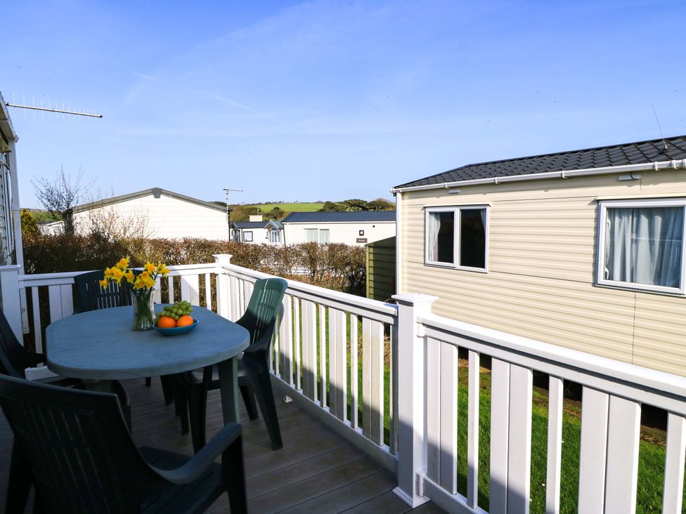 A balcony with table and chairs featuring flowers and fruit at Beachcombers in Wareham