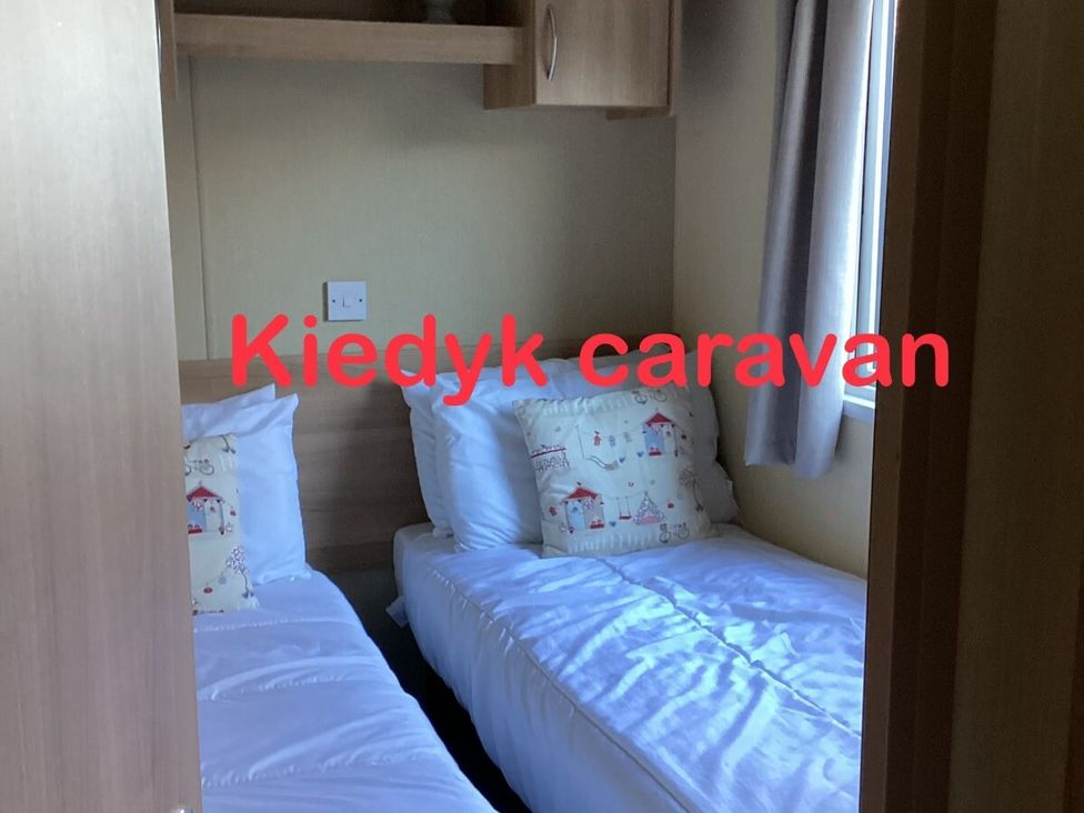 a small bedroom with two single beds and a window at KiedyK caravan in Skegness