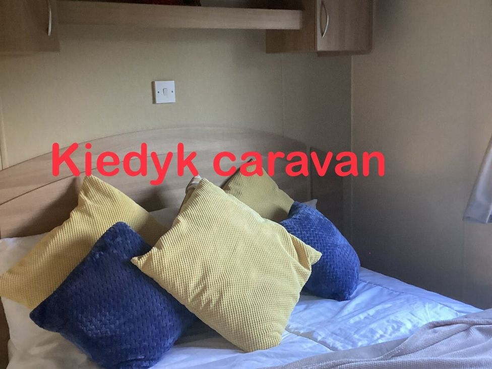 a bedroom with a bed and cushions at Kiedyk caravan in Skegness