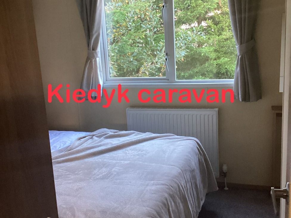 a bedroom with a bed and window at Kiedyk caravan in Skegness