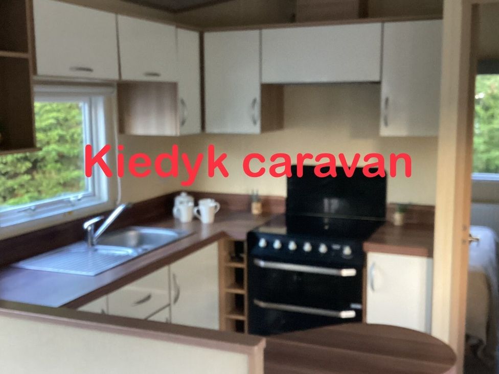 a kitchen area with a sink, stove, and cabinets at Kiedyk caravan in Skegness