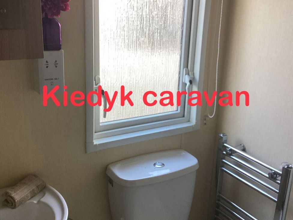 a bathroom with a window, toilet, and towel rack at Southview Holiday Park - Holiday Accommodation 7251, Skegness