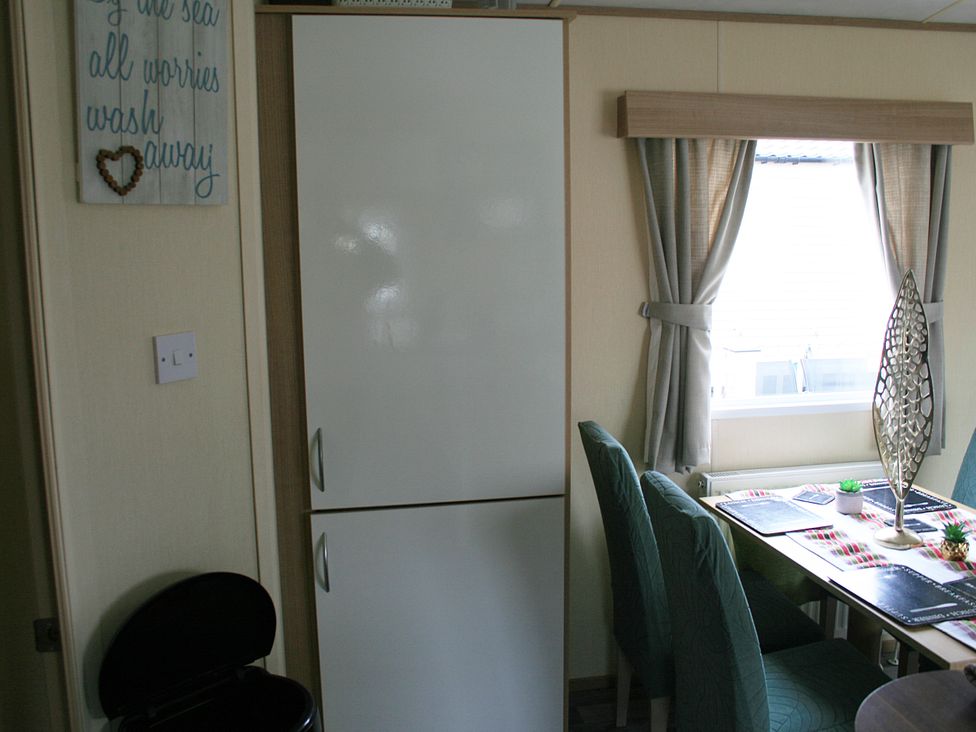 A dining area with a refrigerator and table at Southview Holiday Park 7251 Skegness