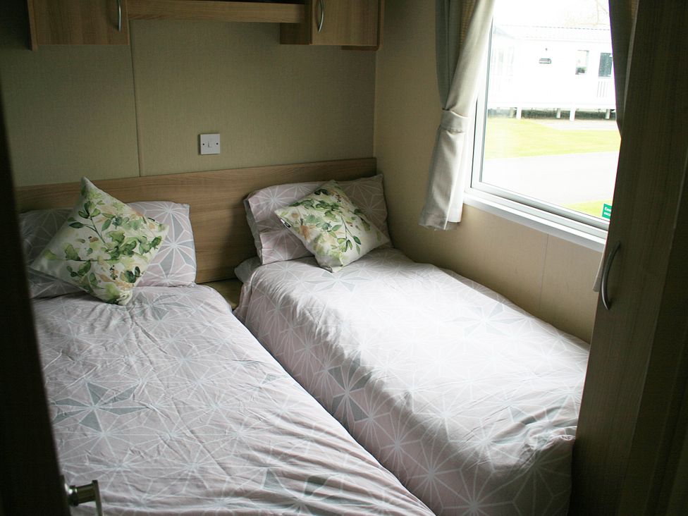 A bedroom with two single beds and a window at Southview Holiday Park 7251 Skegness