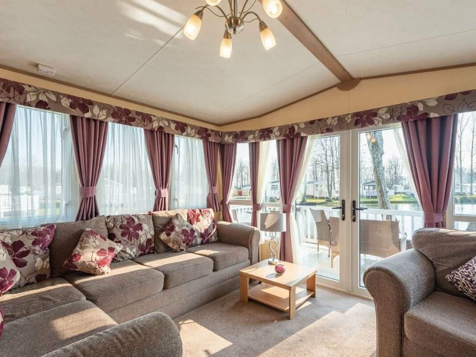 a living room with a sofa and a table near windows at Haggerston Castle - Holiday Accommodation 779, Berwick-upon-Tweed