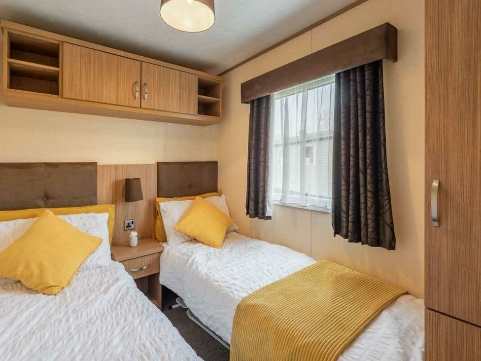 a bedroom with two single beds and yellow cushions at Haggerston Castle - Holiday Accommodation 779 Berwick-upon-Tweed