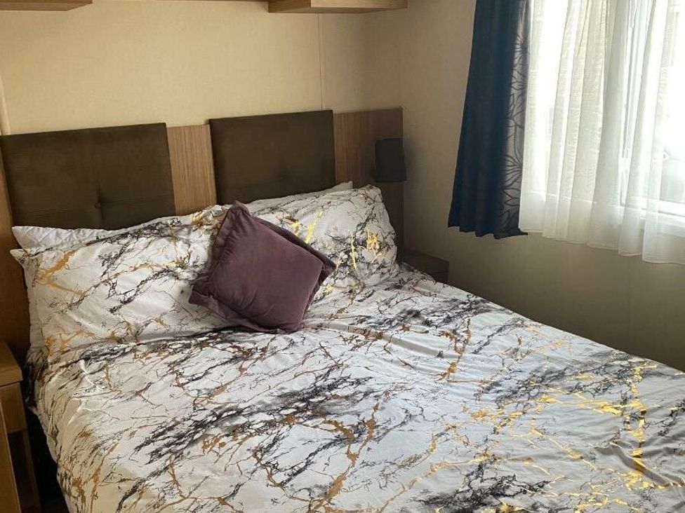 a bedroom with a double bed covered in marble patterned bedding at Haggerston Castle - Holiday Accommodation 779 in Berwick-upon-Tweed