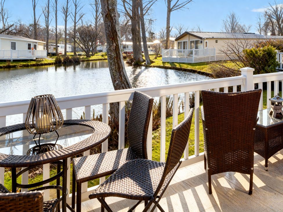 A table and chairs on a balcony overlooking a pond at Haggerston Castle - Holiday Accommodation 779 Berwick-upon-Tweed
