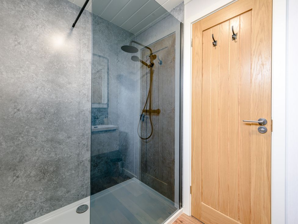 A bathroom with a shower and door at Coniston in Penrith