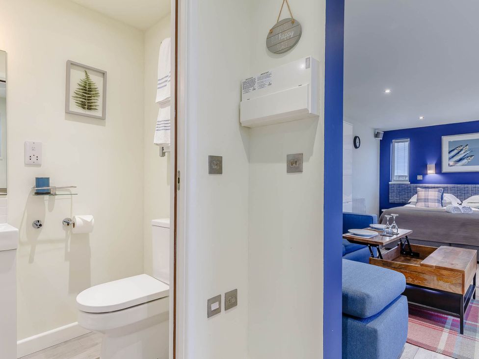A bathroom with a toilet and mirror at Lakeside Studio in Portreath