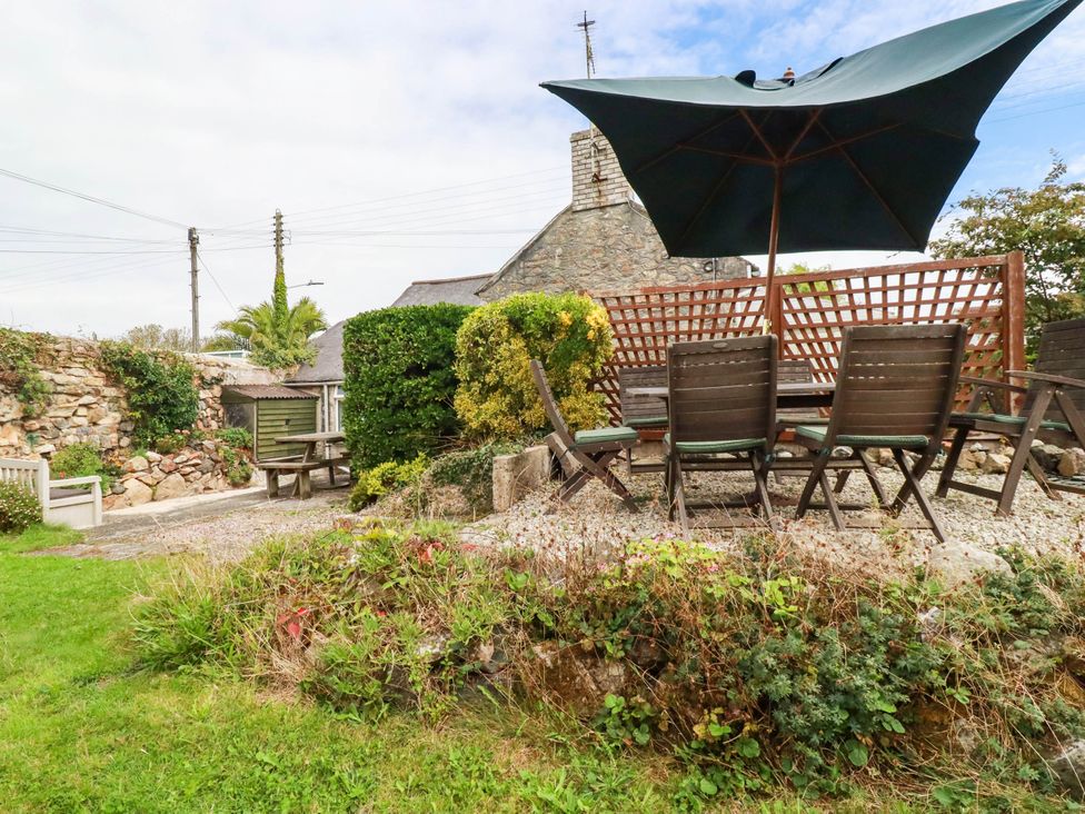 A garden with an outdoor table and chairs under a parasol at Harford