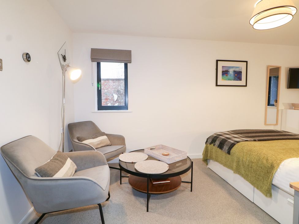 A bedroom with armchairs and a bed at The Bullpen in West Tytherley