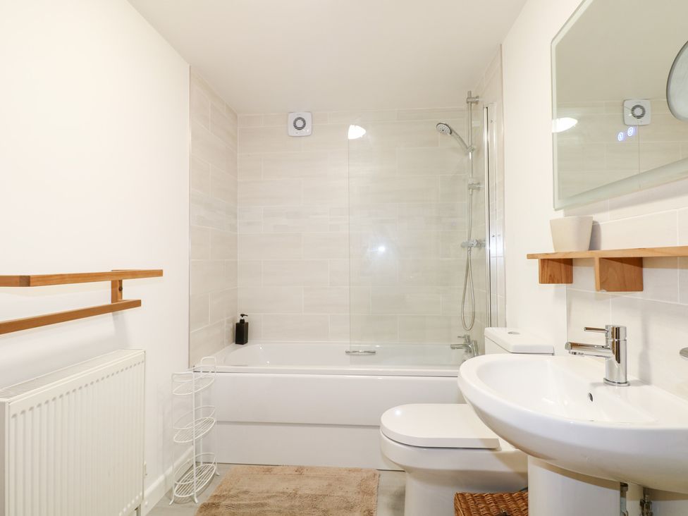 A bathroom with a bathtub, washbasin, and shower at The Bullpen in West Tytherley