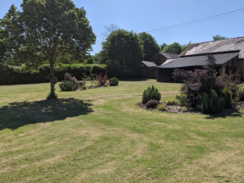 A garden with trees, grass, and shrubs at The Bullpen in West Tytherley