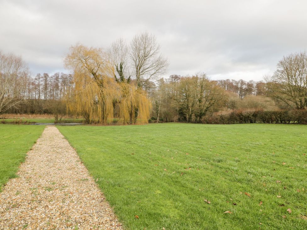 A garden with a gravel path and trees at The Bullpen@Manor Farm West Tytherley
