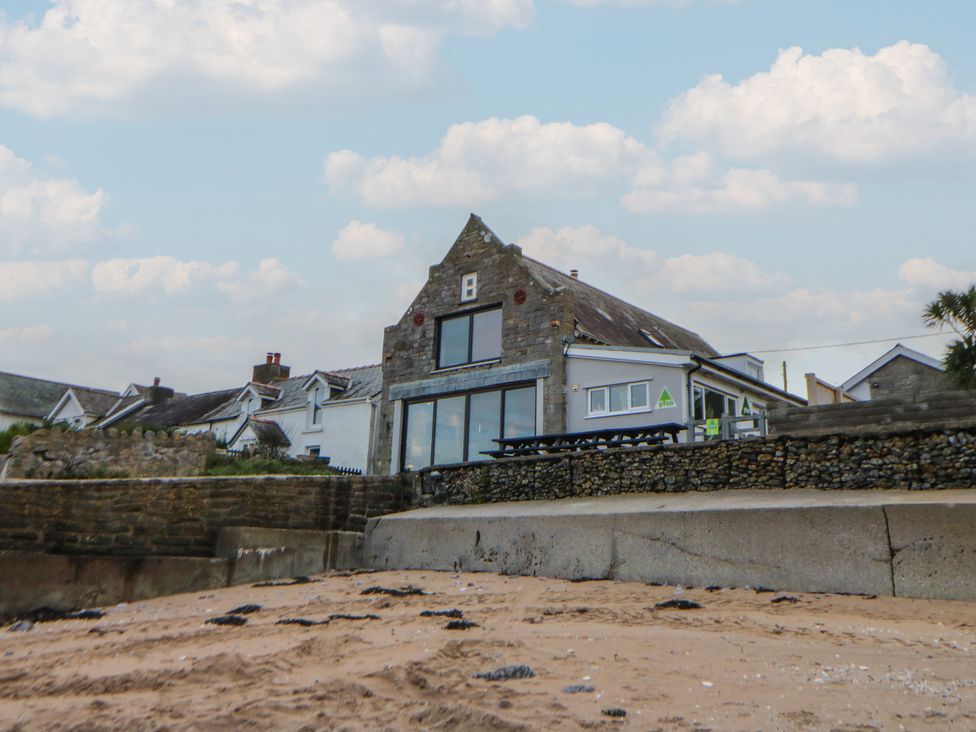 A building with stone walls and outdoor seating at The Boat House - Port Eynon