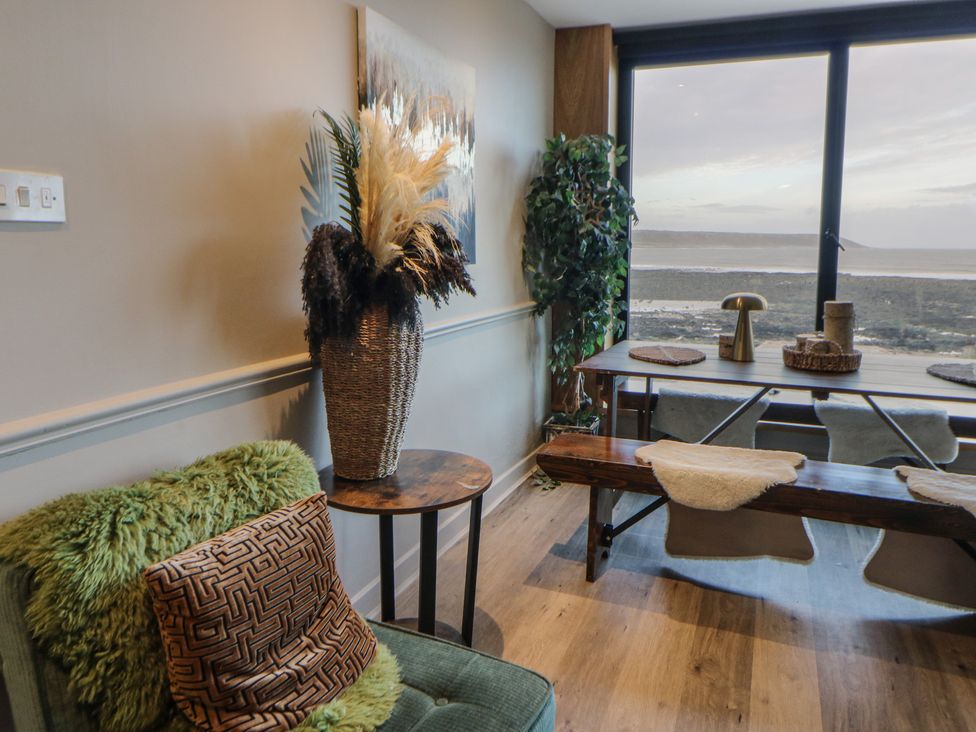 A living room with an armchair and a table at The Boat House - Port Eynon