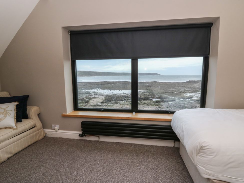 A bedroom with a window overlooking the landscape at The Boat House - Port Eynon