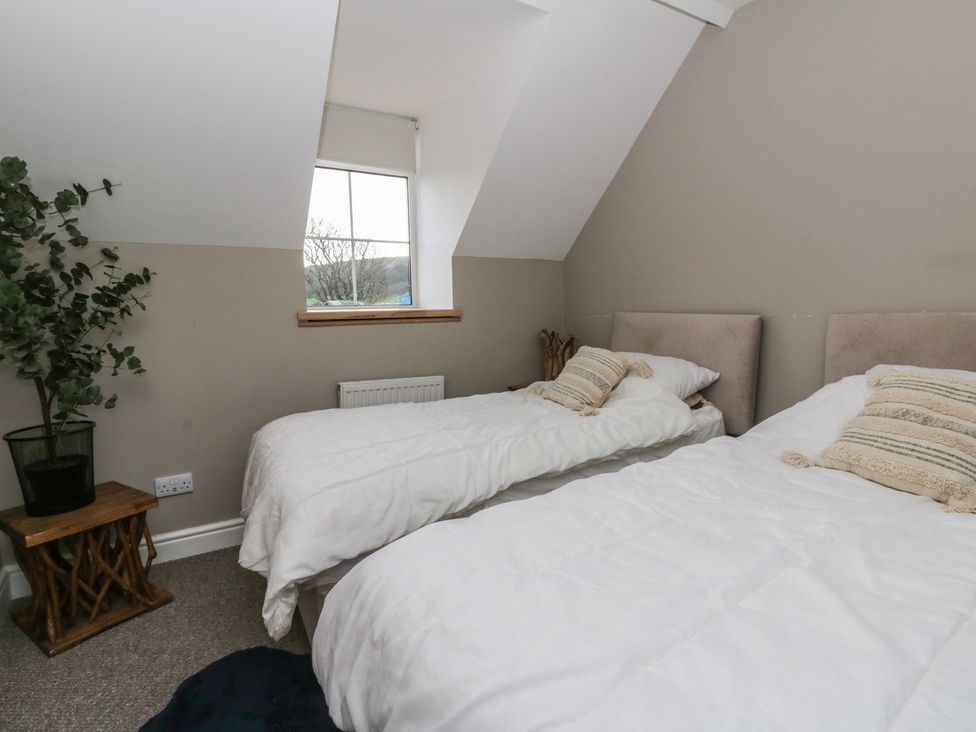 A bedroom with two beds and a plant at The Boat House - Port Eynon