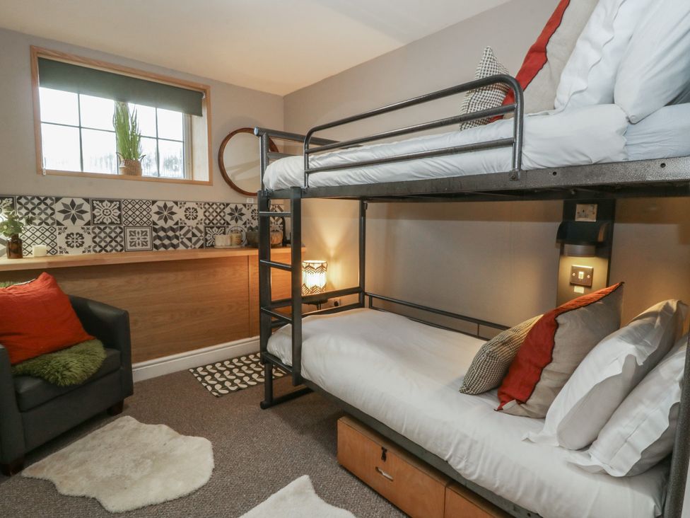 A bedroom with a bunk bed and sofa at The Boat House - Port Eynon