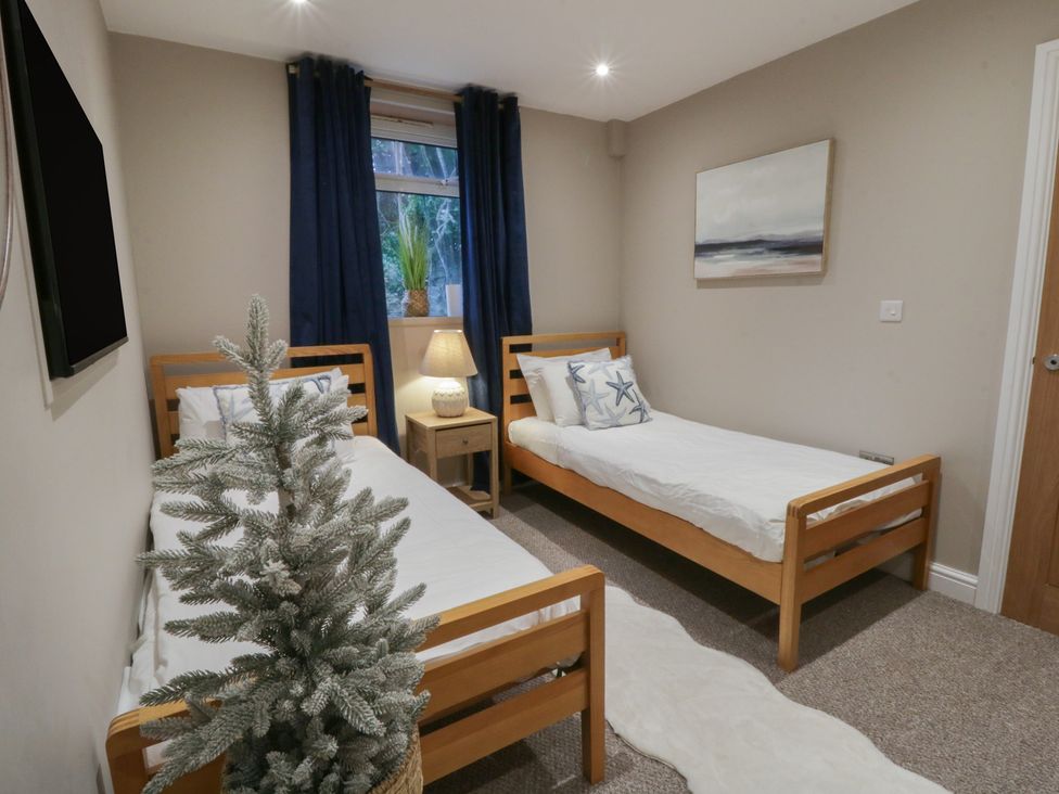 A bedroom with two beds and a nightstand at The Boat House - Port Eynon