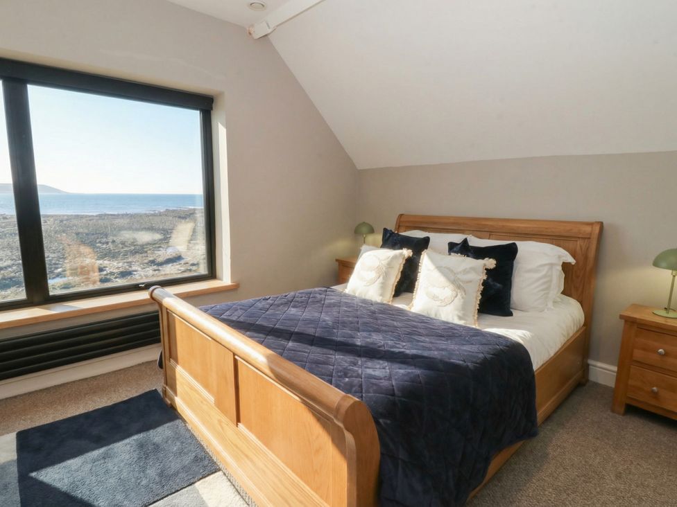 A bedroom with a bed and a large window at The Boat House - Port Eynon