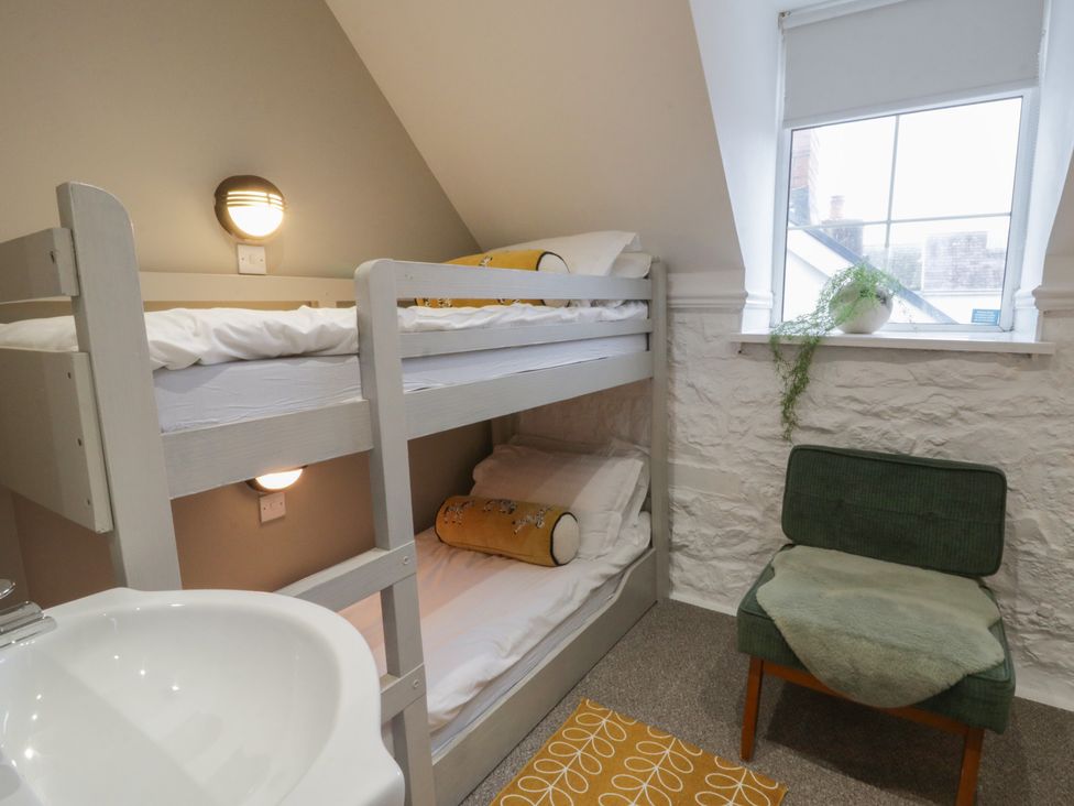 A bedroom with a bunk bed and a chair at The Boat House - Port Eynon