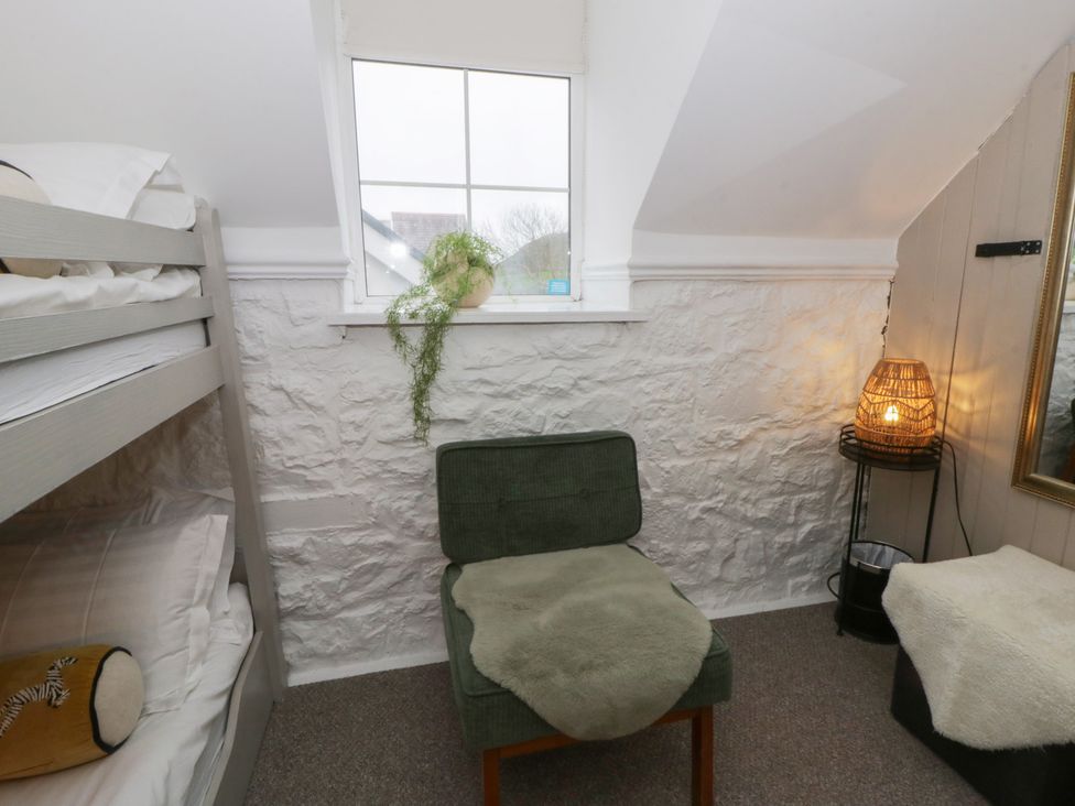 A bedroom with a bunk bed and a green chair at The Boat House - Port Eynon