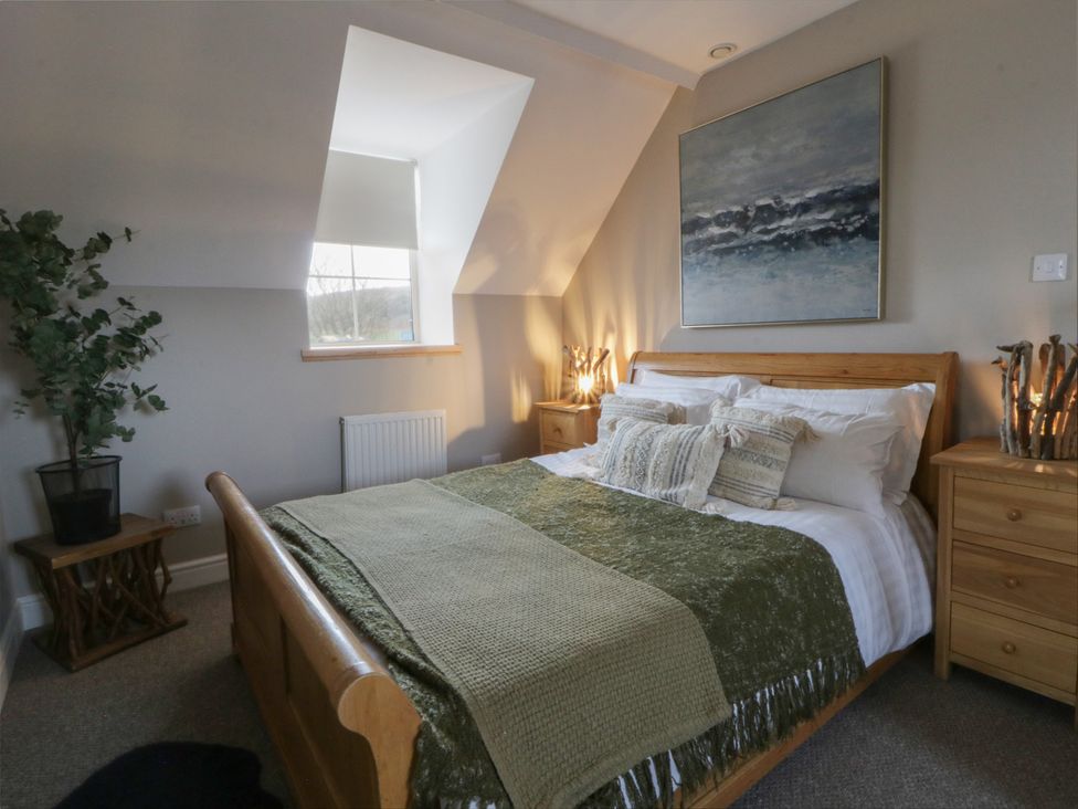 A bedroom with a bed, nightstands and a plant at The Boat House - Port Eynon