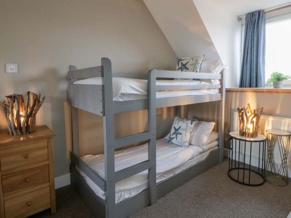 A bedroom with a bunk bed and nightstand at The Boat House - Port Eynon