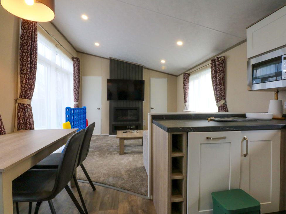 A living room with a dining area and kitchen appliances at Blue Skies in Caernarfon