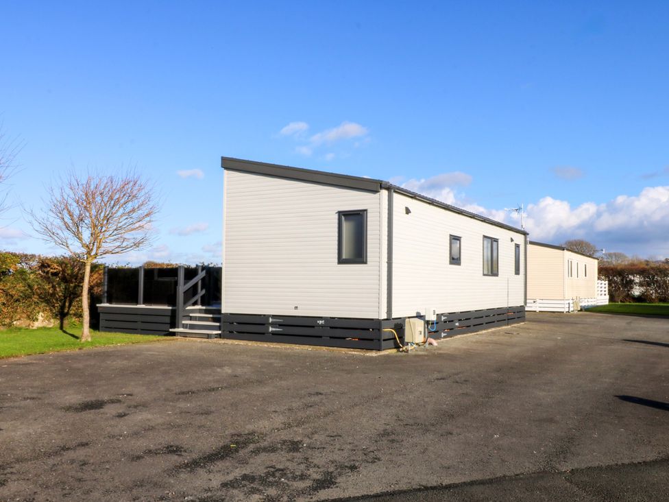 A mobile home with exterior steps and a parking lot at Blue Skies near Caernarfon