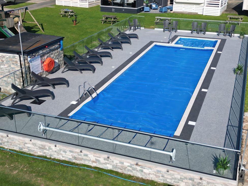 An outdoor swimming pool with a cover and deck chairs at Blue Skies near Caernarfon