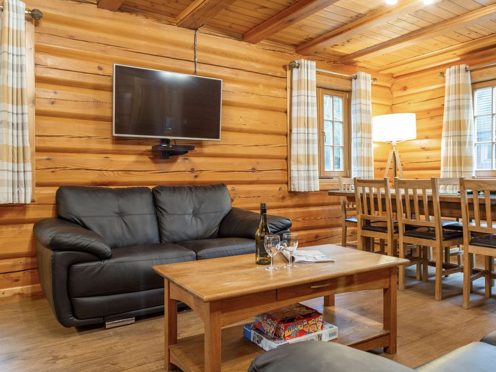 A living room with a sofa and dining area at Kinder Lodge (Pet) Fowlis near Dundee