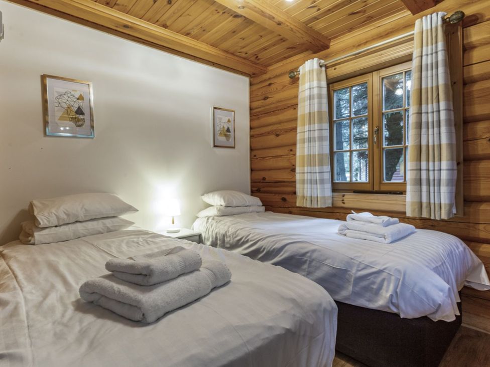 A bedroom with two beds and a lamp at Kinder Lodge (Pet) Fowlis near Dundee