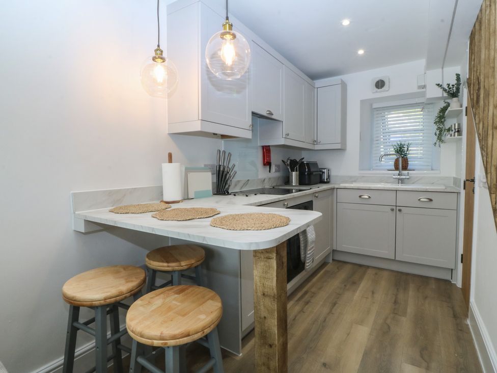 A kitchen with a counter and bar stools at 61A High Street, Criccieth