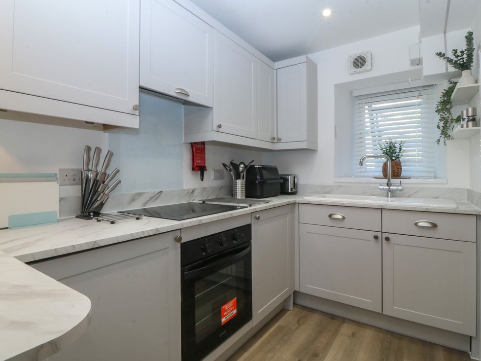 A kitchen with cabinets, oven and sink at 61A High Street in Criccieth