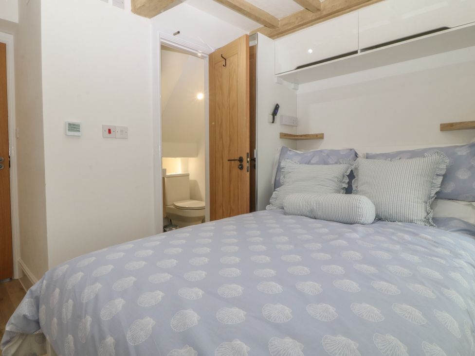 A bedroom with a bed and a door leading to a bathroom at 61A High Street Criccieth