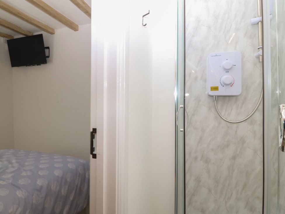 A bathroom with shower and a bed at 61A High Street, Criccieth
