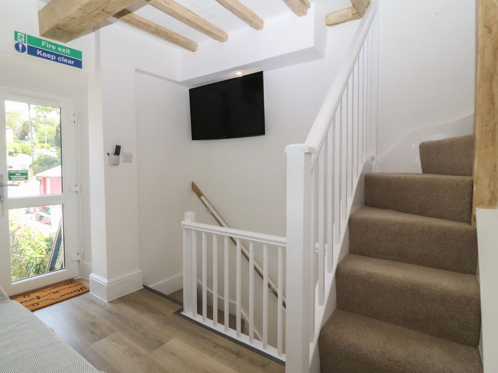 A staircase area with a television and door at 61A High Street Criccieth