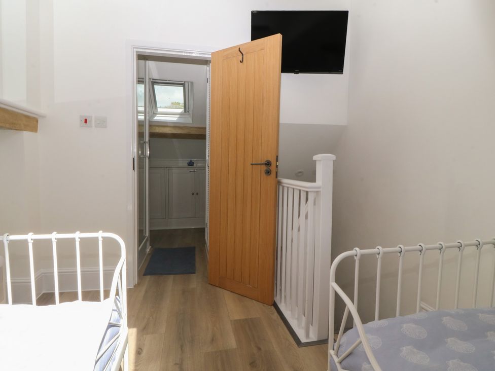 A bedroom with two beds and a door leading to another room at 61A High Street Criccieth