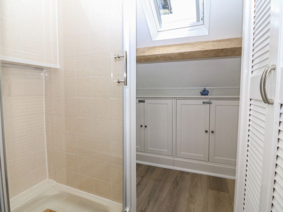 A bathroom with a shower and storage cupboards at 61A High Street in Criccieth