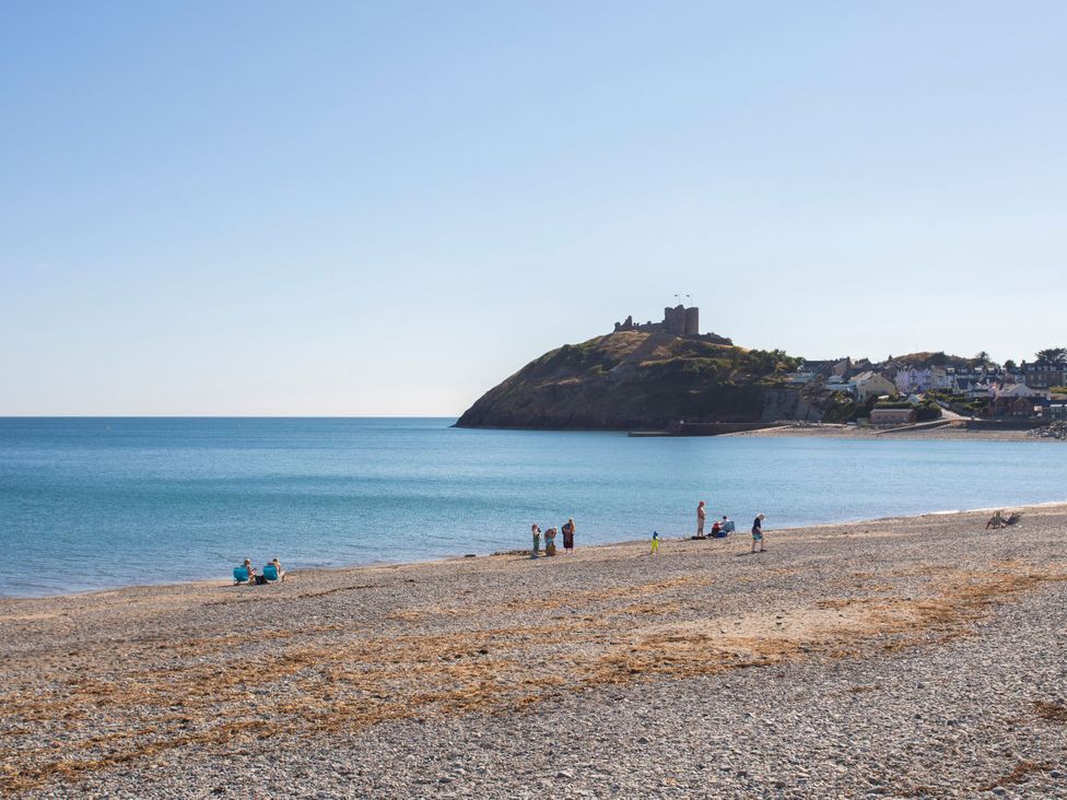 A beach with people and a castle on a hill at 61A High Street Criccieth
