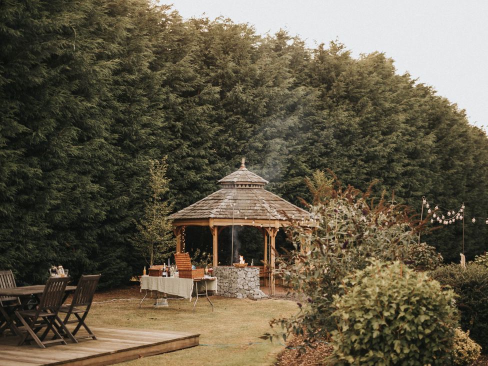 A gazebo in a garden with seating and trees at Garden Pod in Waltham