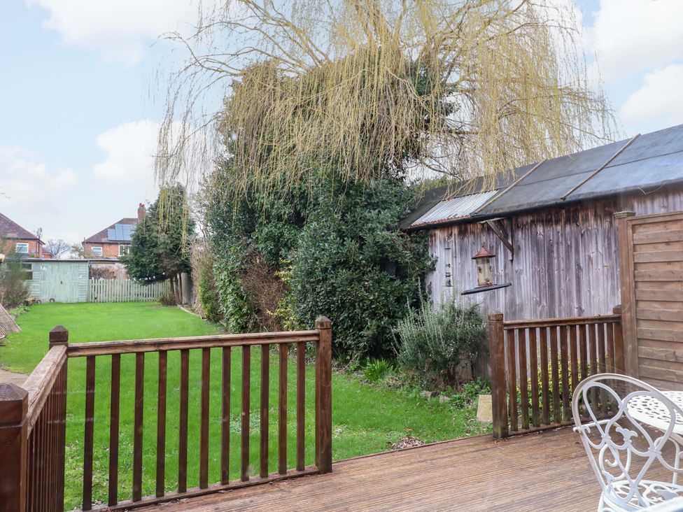 A garden with a wooden decking area and a shed at 5 Wallace Road Loughborough