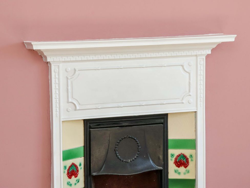 A fireplace with a white mantel and decorative tiles at 22 The Lane Saltburn-by-the-Sea