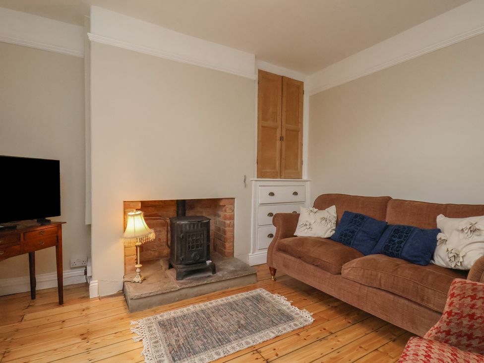 A living room with a wood stove and sofa at The Manse in Whitby