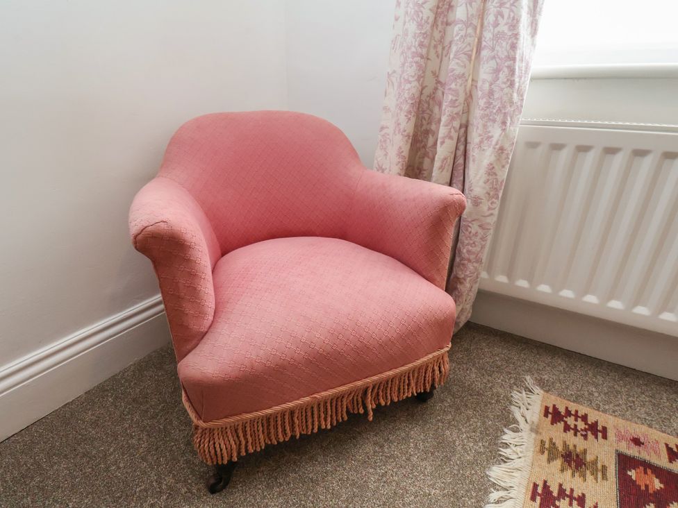 A pink armchair beside a radiator and curtain at The Manse in Whitby